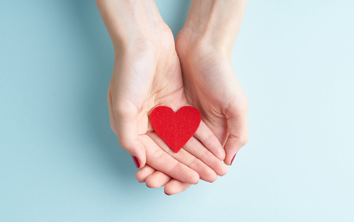 Outstretched hands holding a heart.