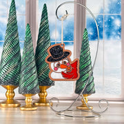 Snowy Snuggles snowman and red cardinal Christmas ornament hanging on a silver stand by a snowy window