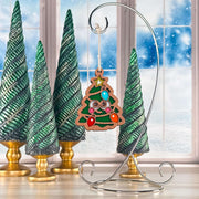 Twinkle Twinkle Christmas tree ornament with a smiling face hanging on a silver stand by a snowy window