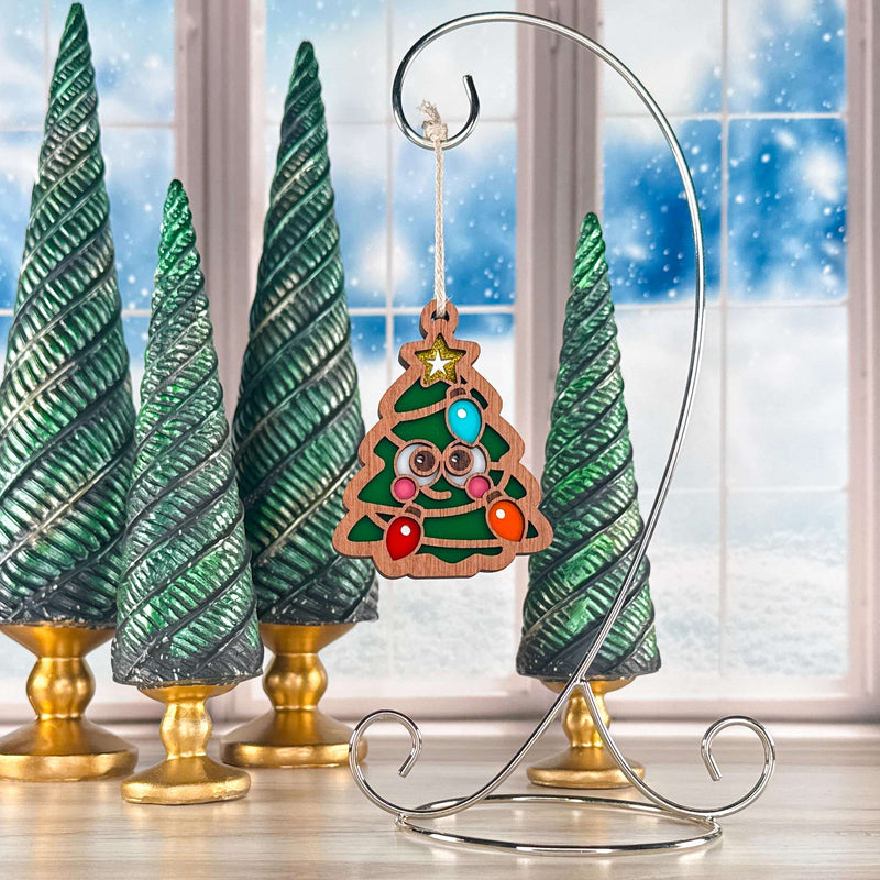 Twinkle Twinkle Christmas tree ornament with a smiling face hanging on a silver stand by a snowy window