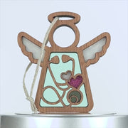 A wooden angel-shaped ornament with white wings and a halo at the top.Perfect as a thoughtful gift for a nurse, it comes with an attached braided linen string for hanging.