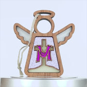 A wooden angel cross ornament with outstretched wings and a halo, featuring an inner cut-out cross design. The cross is draped with a purple cloth. A hanging loop made of braided linen string is attached near the top. The background is plain white.