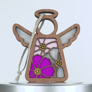 A decorative wooden angel with a colorful stained glass effect in the shape of cosmos flowers fills the body. The angel has outstretched wings and a halo, with a piece of braided linen string attached for hanging. The colors in the stained glass are pink, magenta, and yellow accents.