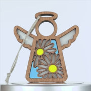 Wooden daisy ornament with cutout wings, a halo, and a string for hanging. The body features two large white daisies with yellow centers on a blue background. The simple, rustic design is set against a white backdrop.